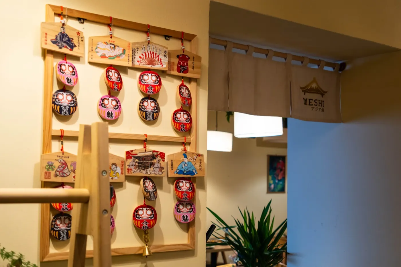 Stěna s panenkami daruma a dřevěnými tabulkami ema